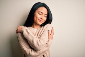 Young woman hugging self with self-love