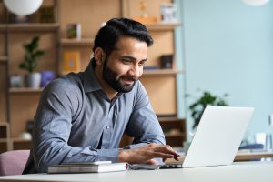 Business man sitting at desk working on computer and smiling